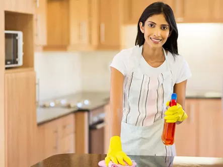 Part-time maid in Singapore wiping kitchen countertop